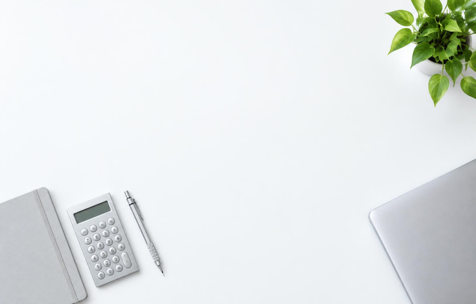 Mesa de trabalho organizada com caderno, calculadora e computador